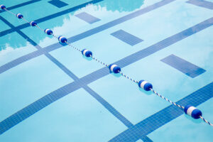 Angled view of an outdoor pool with a rope separating one section from the deep end.