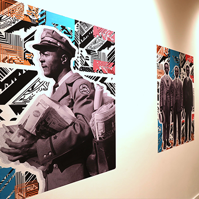 A white wall with various artworks on it. The depict black and white pictures of African American men in suits against colorful backgrounds.