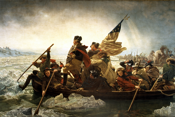 Historic oil painting depicting General George Washington crossing the Delaware river in a wooden rowboat surrounded by members of his army. Washington stands with one foot on the gunwales of the boat. A man behind him carries an American flag. There are large chunks of ice floating in the water.