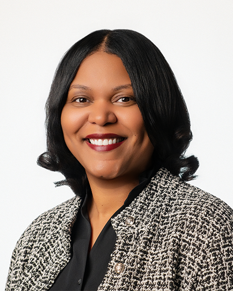 Headshot of a smiling woman wearing a black and white jacket over a black shirt.