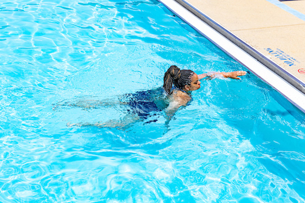 A person swims toward the side of a pool.